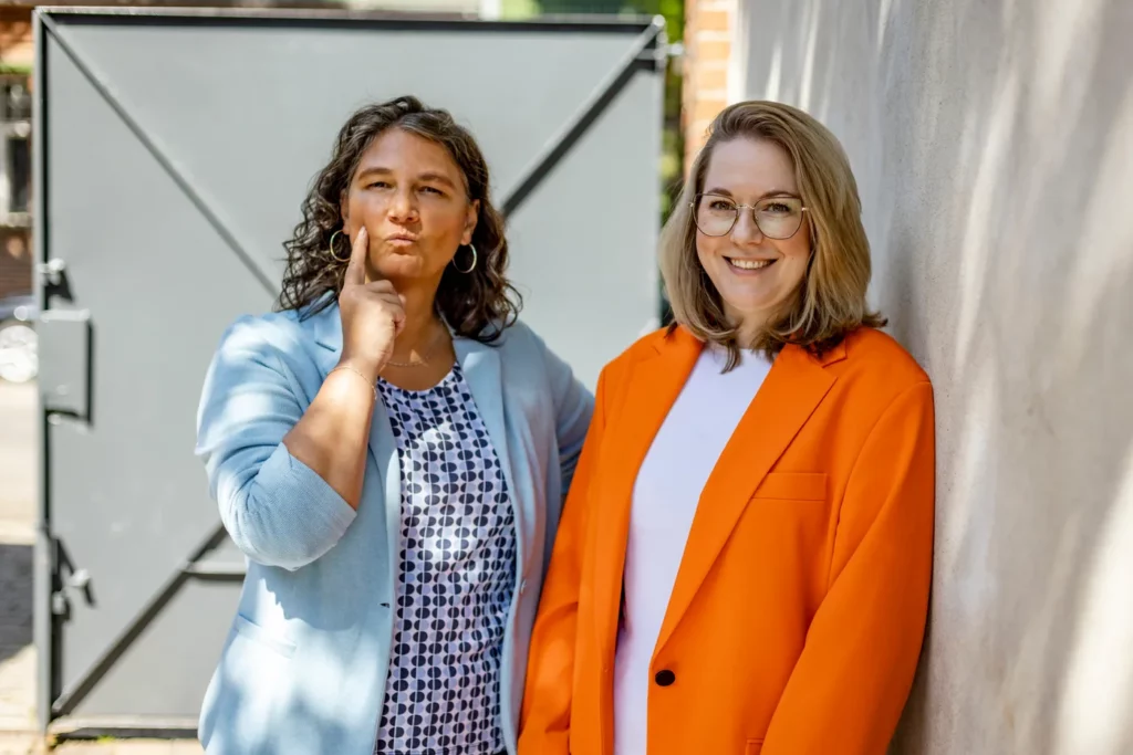 Dominique Woith und Katja Beckmeyer lehnen entspannt an einer Hauswand