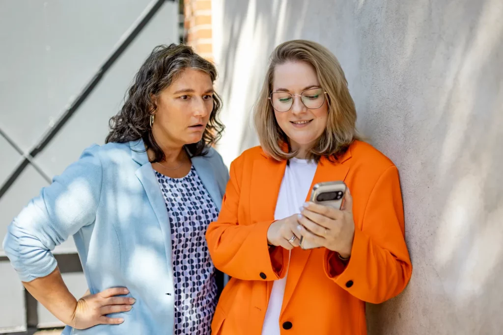 Katja Beckmeyer und Dominique Woith schauen gemeinsam auf ein Smartphone
