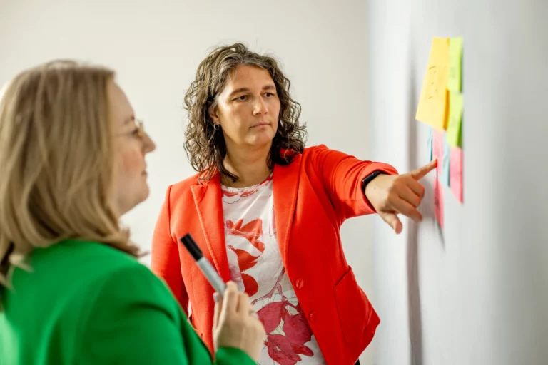 Katja Beckmeyer und Dominique Woith arbeiten an einer Wand mit Haftnotizen